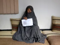 In this photo taken on October 11, 2018. Afghan housewife Fatimah, 55, poses for a picture as she holds her ID card or Tazkira registered to vote in the upcoming parliamentary election, at her House in Mazar-i-Sharif. 
FARSHAD USYAN / AFP