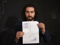 In this photo taken on October 8, 2018, Afghan co-founder and president of ArtLords Omaid Sharifi, 32, poses for a picture as he holds his id card or Tazkira registered to vote in the upcoming parliamentary election, in Kabul. 
WAKIL KOHSAR / AFP
