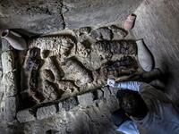 An Egyptian archaeologist cleans mummified cats. (KHALED DESOUKI / AFP)