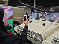 An Iranian woman takes pictures of children sitting in a four-wheel drive vehicle armed with a recoilless rifle, during commemorations of the 40th anniversary of Islamic Revolution in the capital Tehran on February 11, 2019. 
ATTA KENARE / AFP