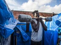 A sub-Saharan migrant lifts weights with a make-shift barbell between make-shift tents in the Oulad Ziane migrant camp in Casablanca on March 27, 2019. 
FADEL SENNA / AFP