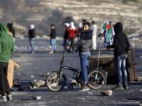 A Palestinian boy rides his bike during clashes with Israeli forces near an Israeli checkpoint in the West Bank city of Ramallah.
(ABBAS MOMANI / AFP)