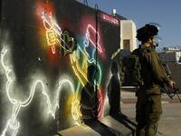 Israeli forces stand guard in front of a mural at the main entrance of Bethlehem, in the Israeli occupied West Bank as protests continue in the region.
(Musa AL SHAER / AFP)