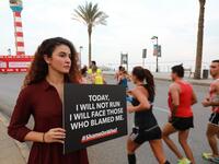 An activist holds a banner against sexual assaults during the 16th edition of the Beirut Marathon on November 11, 2018. 
ANWAR AMRO / AFP