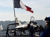 A French flag flies above French naval technicians working on the flight deck of the aircraft (AFP)