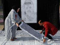 Palestinian Southern Education Direction's member Safa'a Amro (L) prepares a one thousand four hundred Meter square Keffiyeh (named "Arafatian" after the late Palestinian leader) to apply for the Guinness book of World Records' largest Keffiyeh in dura. (HAZEM BADER / AFP)