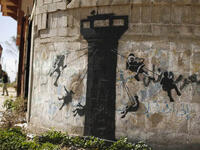 A mural on a wall in Beit Hanoun shows children swinging on a classic Western amusement ride, here done up Palestine style, with an Israeli Defence Forces guard tower planted in its center.