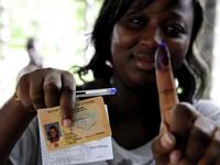 A woman shows documents and a ink-stained finger after voting at a polling station in Abidjan, during the second round of Presidential elections.