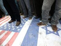 Islamic Jihad supporters walk at the USA and Israeli flag during a demonstration to mark the second anniversary of Israel's three-week offensive on the Gaza Strip.