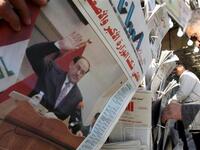 Iraqis pick up newspapers featuring a front-page story on the country's new cabinet at a kiosk in Baghdad, a day after the Iraqi parliament gave Prime Minister Nuri al-Maliki's government a vote of confidence and adopted a 43-point program.