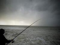  A Lebanese man fishes during a storm on the Mediterranean coast off the northern Lebanese port of Byblos.