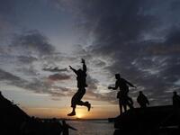 Palestinian boys jump from the top of a sand pile at the beach in Gaza City as they play outdoors during sunset, following storms and heavy rain that poured over the impoverished territory after months of drought.