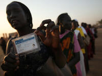 A woman displays her voting card while in line to vote.