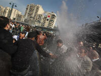 Protesters are hit by a water cannon in front of The l-Istiqama Mosque, as they're watched by riot police in Giza.