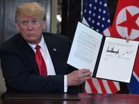 US President Donald Trump holds up a document signed by him and North Korea's leader Kim Jong Un following a signing ceremony during their historic US-North Korea summit, at the Capella Hotel on Sentosa island in Singapore on June 12, 2018. (SAUL LOEB / AFP)