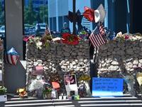 A passerby is reflected in glass as he collects himself before a makeshift memorial to Senator John McCain outside McCain's office in Phoenix, Arizona, August 27, 2018. McCain, a two-time US presidential candidate and war hero, passed away August 25 at the age of 81.  (Robyn Beck / AFP)