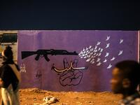 Sudanese protestors walk in front of a recently painted mural during a protest outside the army complex in the capital Khartoum. OZAN KOSE / AFP