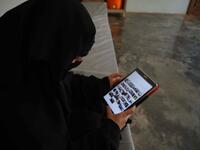 Hasna Dbeis, a 30-year-old former detainee in a Syrian-regime jail, looks at photographs on an electronic tablet device at her home  Aaref WATAD / AFP