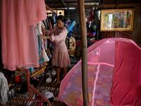 This picture shows a woman arranging clothes inside her home in front of a grave in Phnom Penh.  TANG CHHIN Sothy / AFP