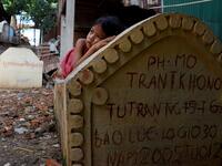 This picture shows a girl lying on a grave in Phnom Penh.  TANG CHHIN Sothy / AFP