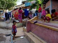 This picture shows children playing on a grave as a woman dries her clothes on another grave in Phnom Penh.  TANG CHHIN Sothy / AFP