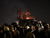 People watch as Notre-Dame de Paris Cathedral burns late into the night on April 15, 2019, in the French capital Paris.  A huge fire swept through the roof of the famed Notre-Dame Cathedral in central Paris on April 15, 2019. ludovic MARIN / AFP