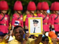 A man holds a portrait of Thailand's King Maha Vajiralongkorn as he waits for the King and Queen Suthida to appear on the balcony of Suddhaisavarya Prasad Hall of the Grand Palace for a public audience on the final day of his royal coronation in Bangkok on May 6, 2019.  Manan VATSYAYANA / AFP