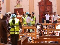 Sri Lankan security personnel walk past debris next to a dead body slumped over a bench following an explosion in St Sebastian's Church in Negombo, north of the capital Colombo, on April 21, 2019. STR / AFP