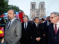 French Prime Minister Edouard Philippe (L), and French President Emmanuel Macron (3rd L) gather near the entrance of the Notre-Dame de Paris Cathedral in Paris, as flames engulf its roof on April 15, 2019. PHILIPPE WOJAZER / POOL / AFP