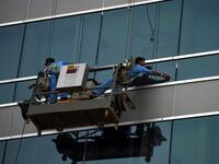 Pakistani labourers clean the windows of a bulding in Karachi on April 30, 2019, on the eve of the International Labour Day celebrated on May 1.  RIZWAN TABASSUM / AFP