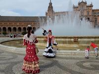 Tourists in traditional Sevillian dresses take photos at the Plaza de Espana square during the "Feria de Abril" (April Fair) festival in Seville on May 6, 2019. CRISTINA QUICLER / AFP