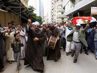 An Egyptian man dances with a national flag as others play musical instruments while walking in a procession outside a school in the second city of Alexandria, during voting in a referendum on constitutional amendments. Tarek ABDEL HAMID / AFP