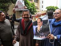Egyptians pose for a picture with a newspaper front page and a poster of President Abdel Fattah al-Sisi outside a school in the second city of Alexandria during voting in a referendum on constitutional amendments on the first day of the three-day poll, on April 20, 2019. Tarek ABDEL HAMID / AFP