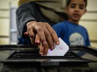 An man Egyptian casts his ballot with a child at a polling station during the third day of a referendum on constitutional amendments, at a school in shamma village in the northern Nile delta province of Menoufia, on April 22, 2019.  Mohamed el-Shahed / AFP