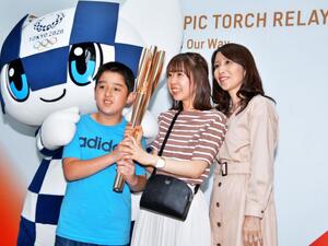Visitors pose for a photo with a torch of the Tokyo 2020 Olympic Games during a news conference on the torch relay Saturday in Tokyo, Japan. Photo by Keizo Mori/UPI