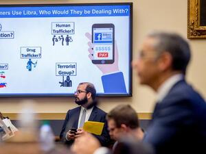  A screen the reads "If Consumers Use Libra, Who Would They Be Dealing With?" is displayed with questions on potential user actors as David Marcus, CEO of Facebook's Calibra digital wallet service, foreground, appears before a House Financial Services Committee hearing on Facebook's proposed cryptocurrency on Capitol Hill in Washington, Wednesday, July 17, 2019.