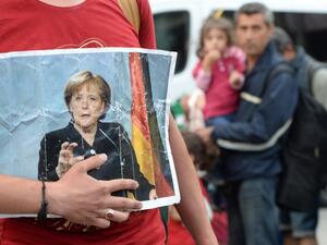 A refugee holds a picture of German Chancellor Angela Merkel after the arrival of refugees at the main train station in Munich, southern Germany, September 5, 2015. (AFP/ File)