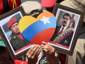 A supporter of Venezuelan President Nicolas Maduro displays pictures of Maduro (R) and late leader Hugo Chavez during a rally on May Day in Caracas on May 1, 2019. (AFP/ File Photo)
