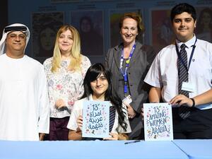 دانة البلوشي مع كتابها "13 امرأة عربية ملهمة".