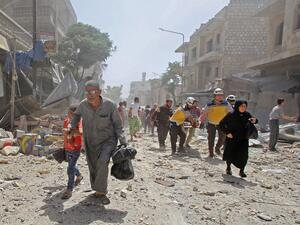 Members of the Syrian Civil Defence (known as the White Helmets) carry a wounded man on a stretcher (background) as people flee a bombarded neighbourhood following a reported air strike by pro-government forces on the town of Maaret al-Numan in the jihadist-held Idlib province on June 3, 2019. (Abdulaziz KETAZ / AFP)