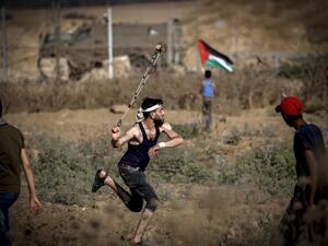 A Palestinian man hurls a stone during clashes with Israeli forces near the fence along the border with Israel near Bureij in the central Gaza Strip on June 14, 2019. (MOHAMMED ABED / AFP)