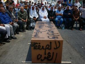 Palestinian men sit around a makeshift coffin with the words "No to the deal of the century", during a protest against a US-led meeting this week in Bahrain on the Palestinian-Israeli conflict, in the village of Yatta near the West Bank city of Hebron, on June 24, 2019. (AFP/ File Photo)