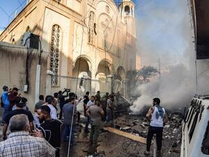 People extinguish a fire at the scene of a car bomb explosion outside the Syriac Orthodox Church of the Virgin Mary in the predominantly Christian neighbourhood of al-Wasti in the Kurdish-majority city of Qamishli in northeast Syria on July 11, 2019. (AFP)