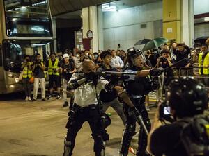 A police officer (C) points a firearm during clashes with protesters who had gathered outside Kwai Chung police station, in support of protesters detained with the charge of rioting, in Hong Kong on July 30, 2019. (ISAAC LAWRENCE / AFP)