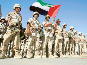 A contingent force from the United Arab Emirates holding their national flag, stand at ease on the tarmac of Kuwait International Airport upon their arrival here 23 February 2003. (AFP/ File Photo)