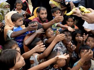 Rohingya refugees receive bananas from a Bangladeshi volunteer after crossing from Myanmar into Bangladesh at Shah Porir Dwip Island near Teknaf . (Tauseef Mustafa / AFP/Getty Images).