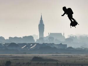 Franky Zapata on his jet-powered "flyboard" flies past the belfry of the city hall of Calais (C) after he took off from Sangatte, northern France (AFP)