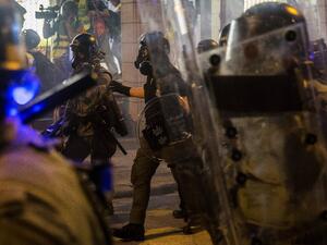 Riot police walk amid tear gas fired at protesters in an attempt to disperse them in Hong Kong (AFP)