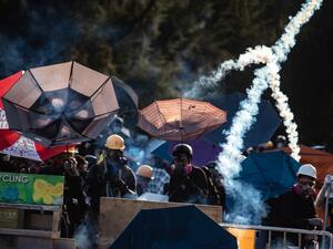 Protesters stand amid tear gas fired by the police in Tai Po district during a general strike in Hong Kong (AFP)