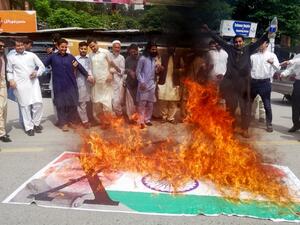 Kashmiris chant slogans beside a burning Indian flag with a photograph of Indian Prime Minister Narendra Modi during a protest in Muzaffarabad, the capital of Pakistan controlled Kashmir (AFP)